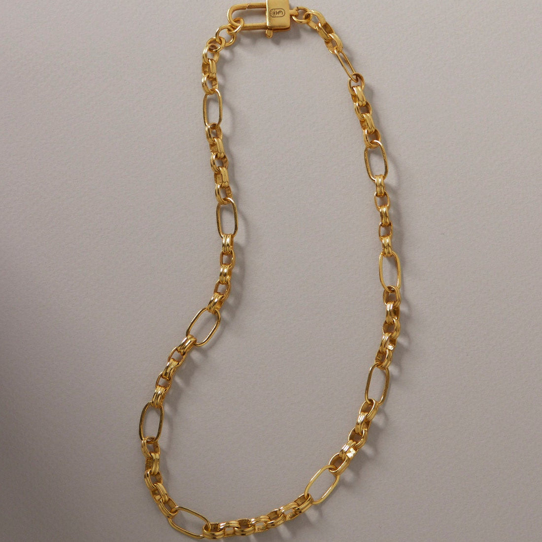 Gold chain necklace on a gray background