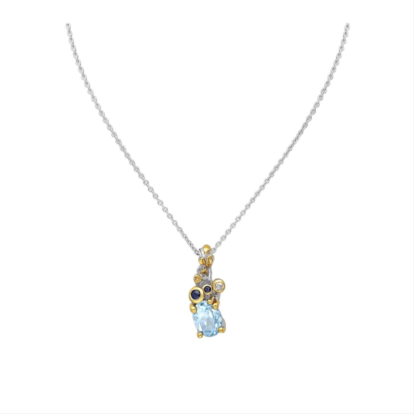 A sterling silver necklace with a 22K yellow gold plate and a drop-shaped sky blue topaz pendant, accompanied by small round blue sapphire gemstones.