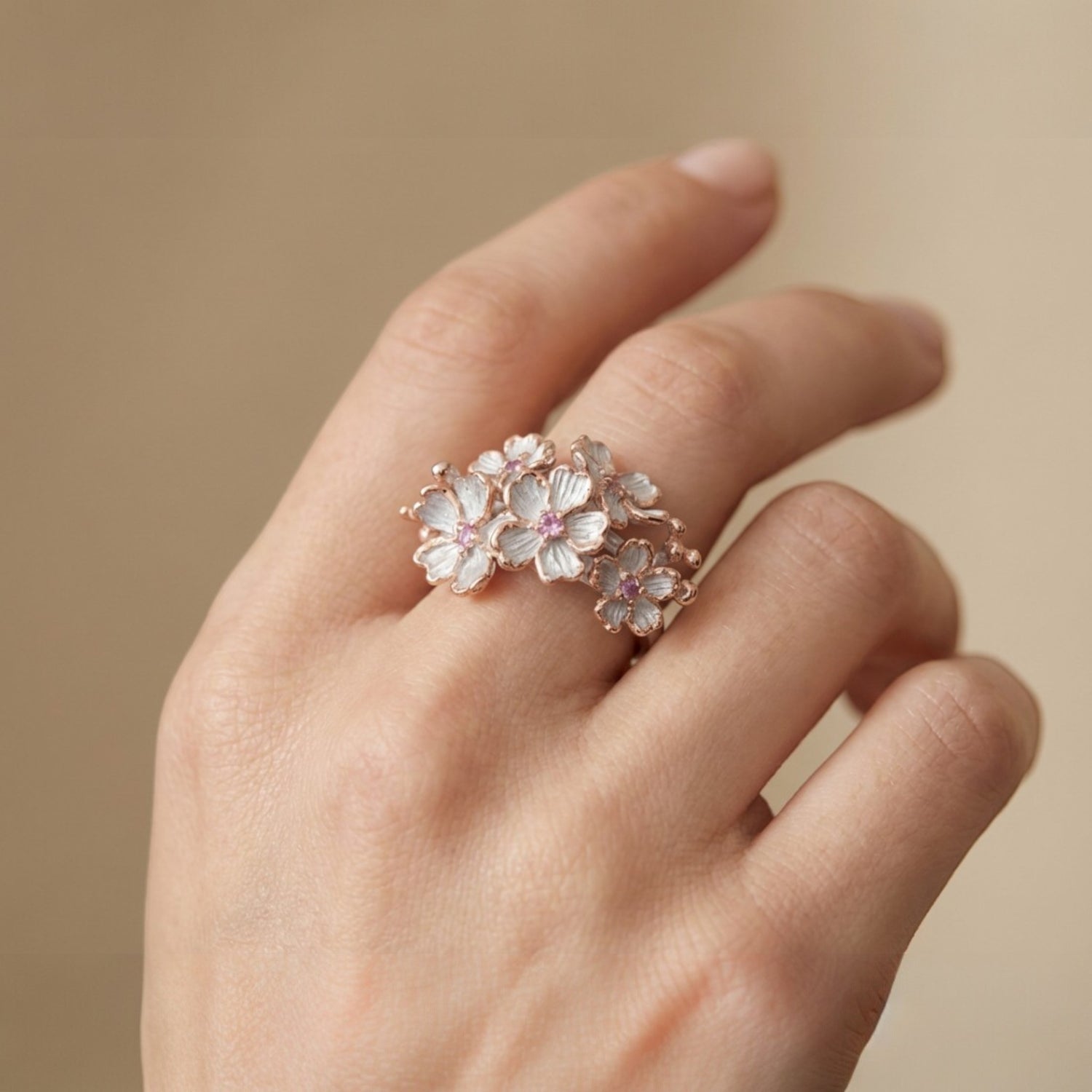 Tania Claire Australia Blossom Ring: Sterling silver floral ring with white enamel petals, pink sapphires, and rose gold accents.