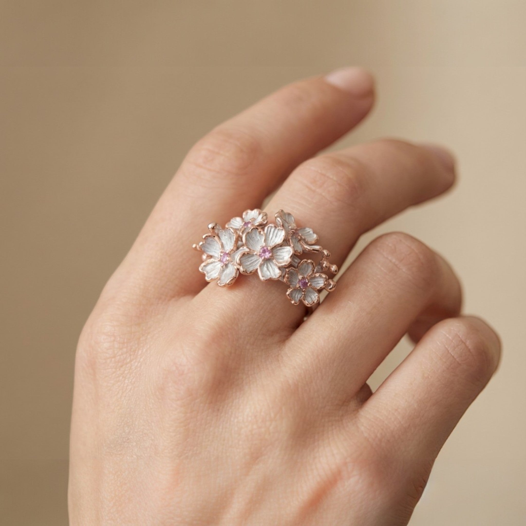 Tania Claire Australia Blossom Ring: Sterling silver floral ring with white enamel petals, pink sapphires, and rose gold accents.