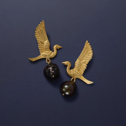 Tania Claire Australia gold-tone earrings with winged bird motif holding black baroque pearls.