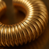 Tania Claire Australia gold-tone ear cuff featuring a chunky, sculptural ribbed texture in a circular design.