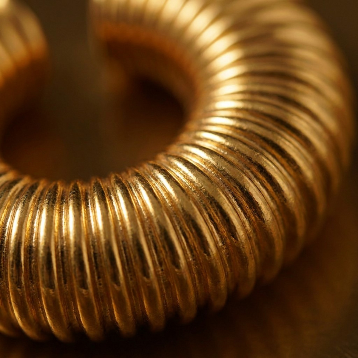 Tania Claire Australia gold-tone ear cuff featuring a chunky, sculptural ribbed texture in a circular design.