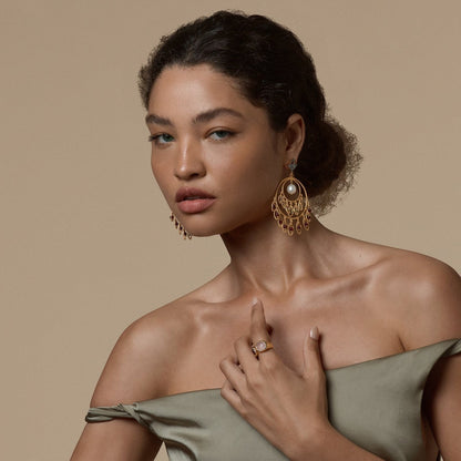 Tania Claire Australia Sacred Bloom earrings with garnet, peridot, and pearl on a model wearing a silk dress.