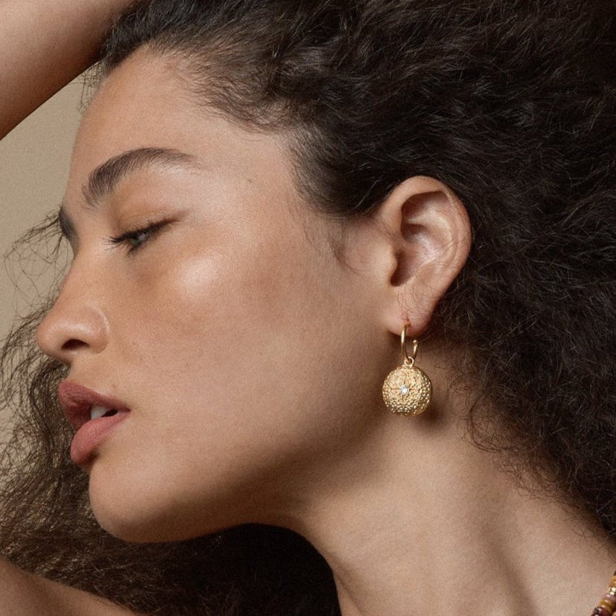 Tania Claire Australia Stella Medallion earrings: hammered gold discs with celestial starburst engraving and crystal center. 14K gold plated brass.