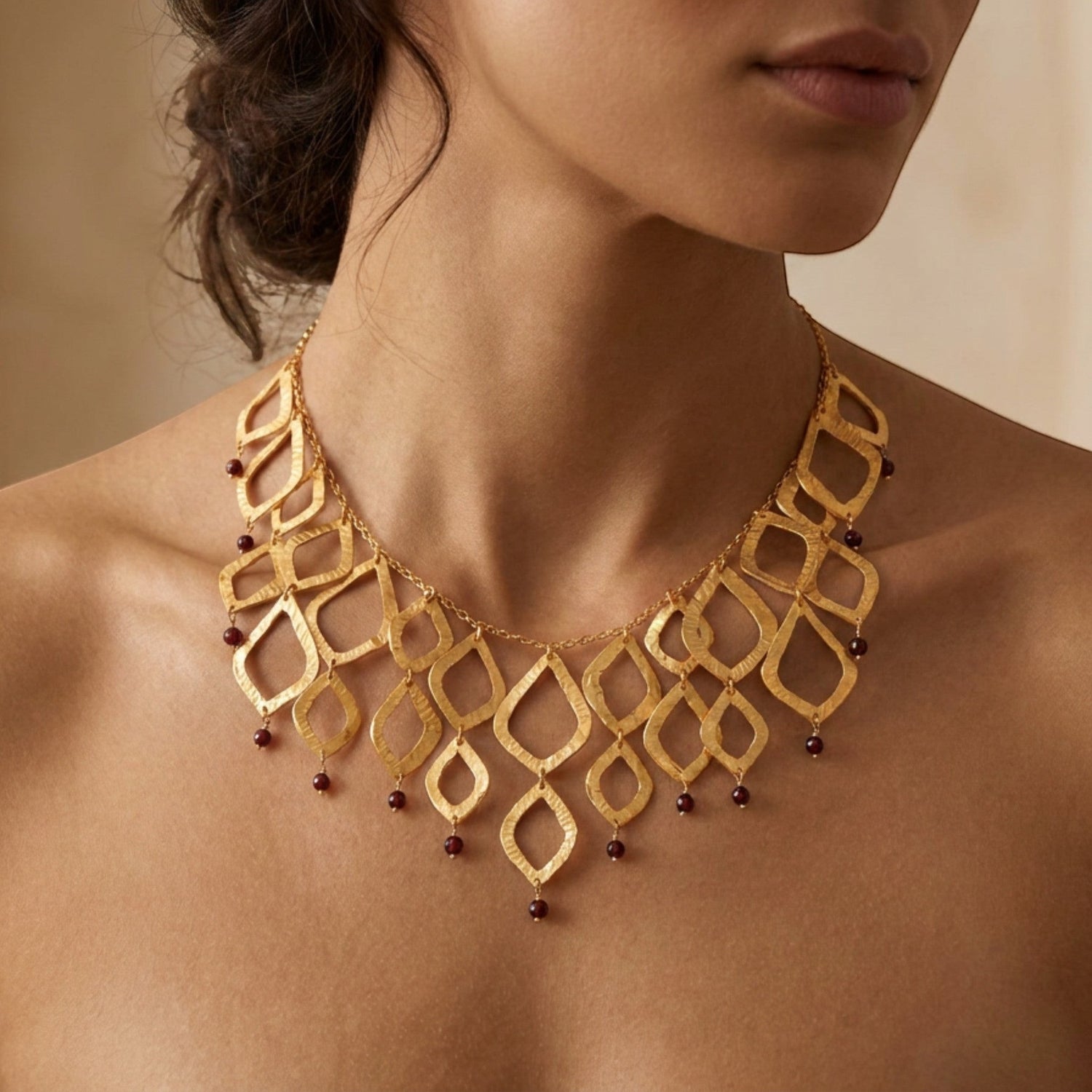 Tania Claire Australia Temple Flame necklace featuring architectural gold brass lattice with garnet gemstone accents.